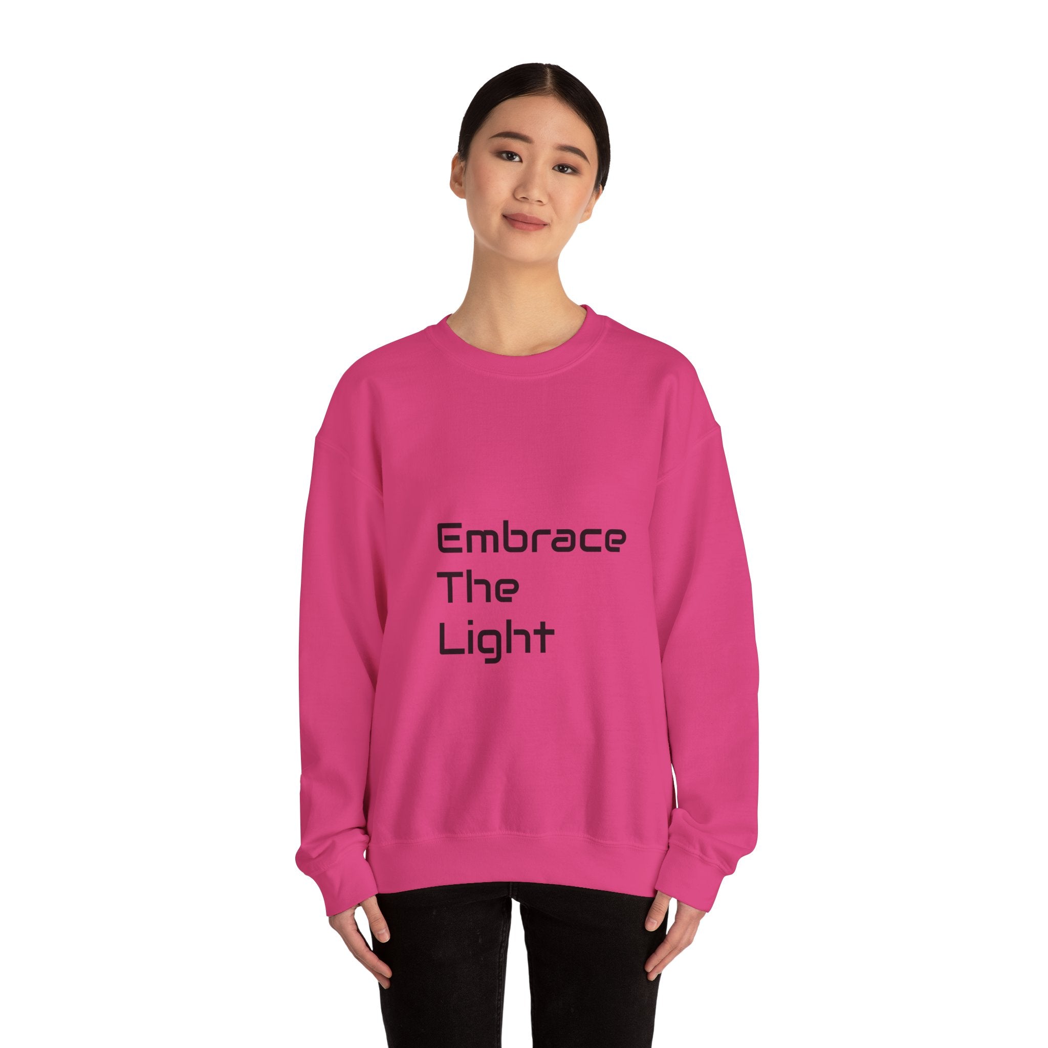 Unisex crewneck sweatshirt in vibrant pink with 'Embrace The Light' text print. Made from a cozy 50/50 cotton blend for comfort and durability.