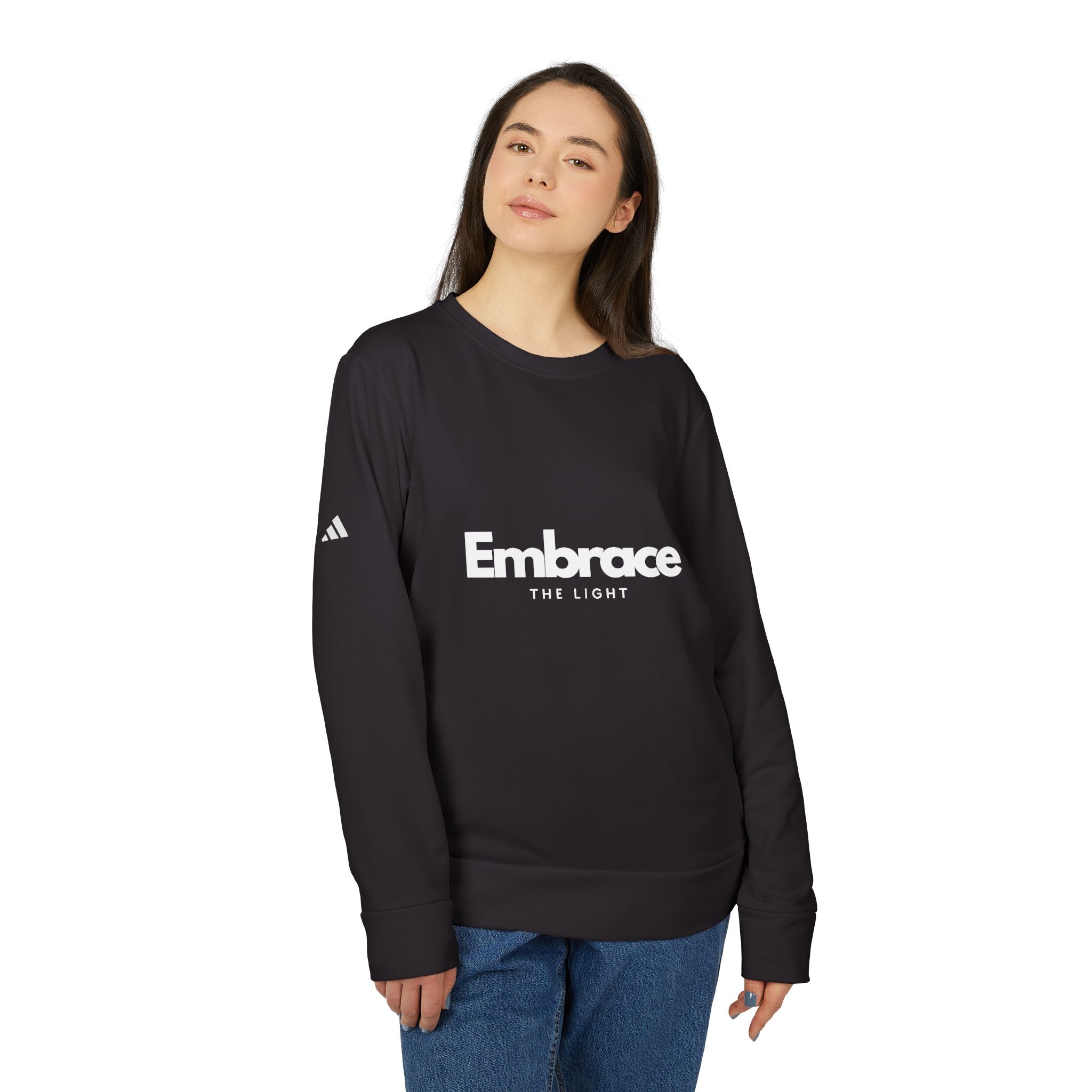 Adidas fleece sweatshirt in black with 'Embrace The Light' print. Eco-friendly crewneck made from BCI cotton and recycled polyester for warmth and sustainability.