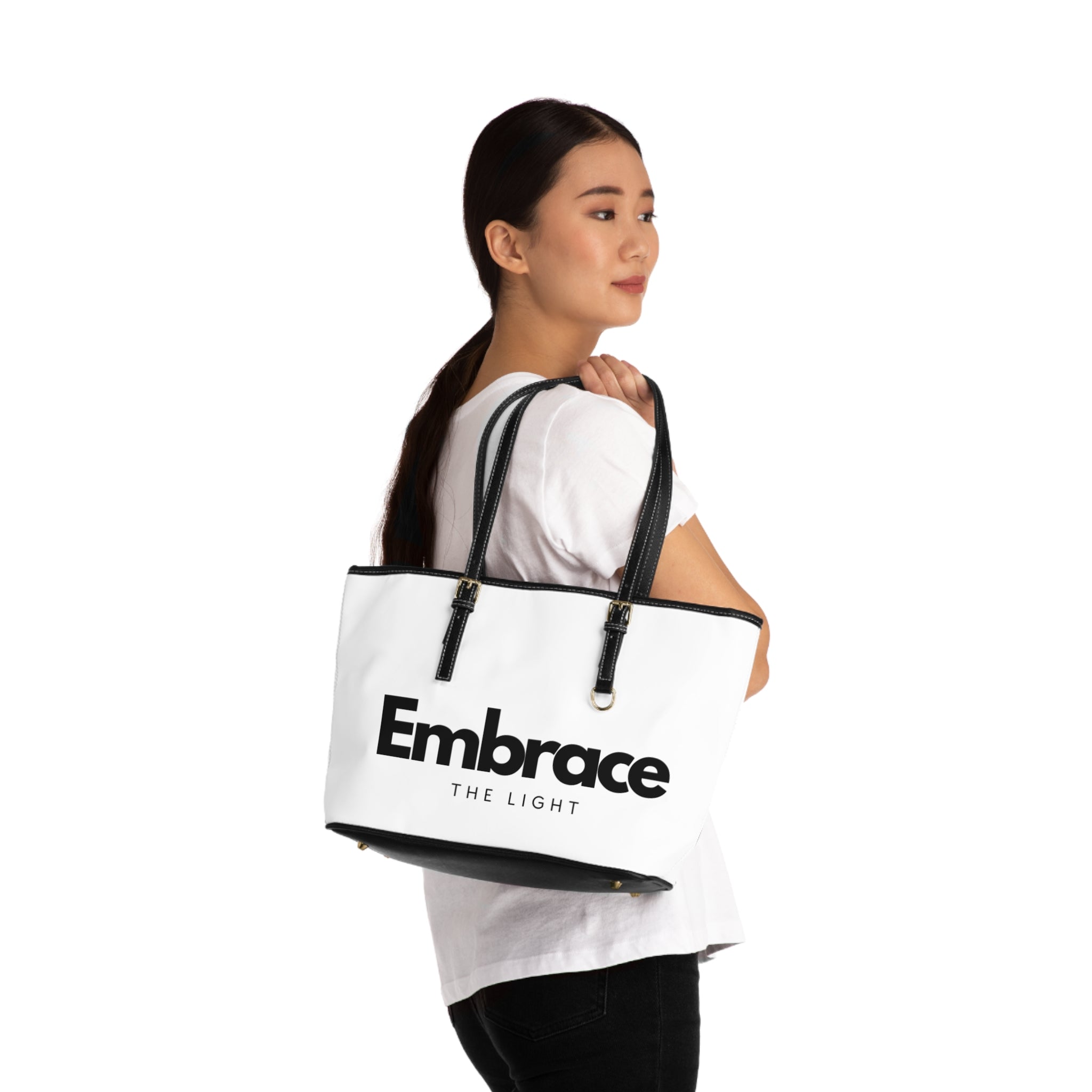 Stylish PU leather shoulder bag with 'Embrace The Light' text, featuring black handles and gold accents. Spacious and durable design for everyday use.