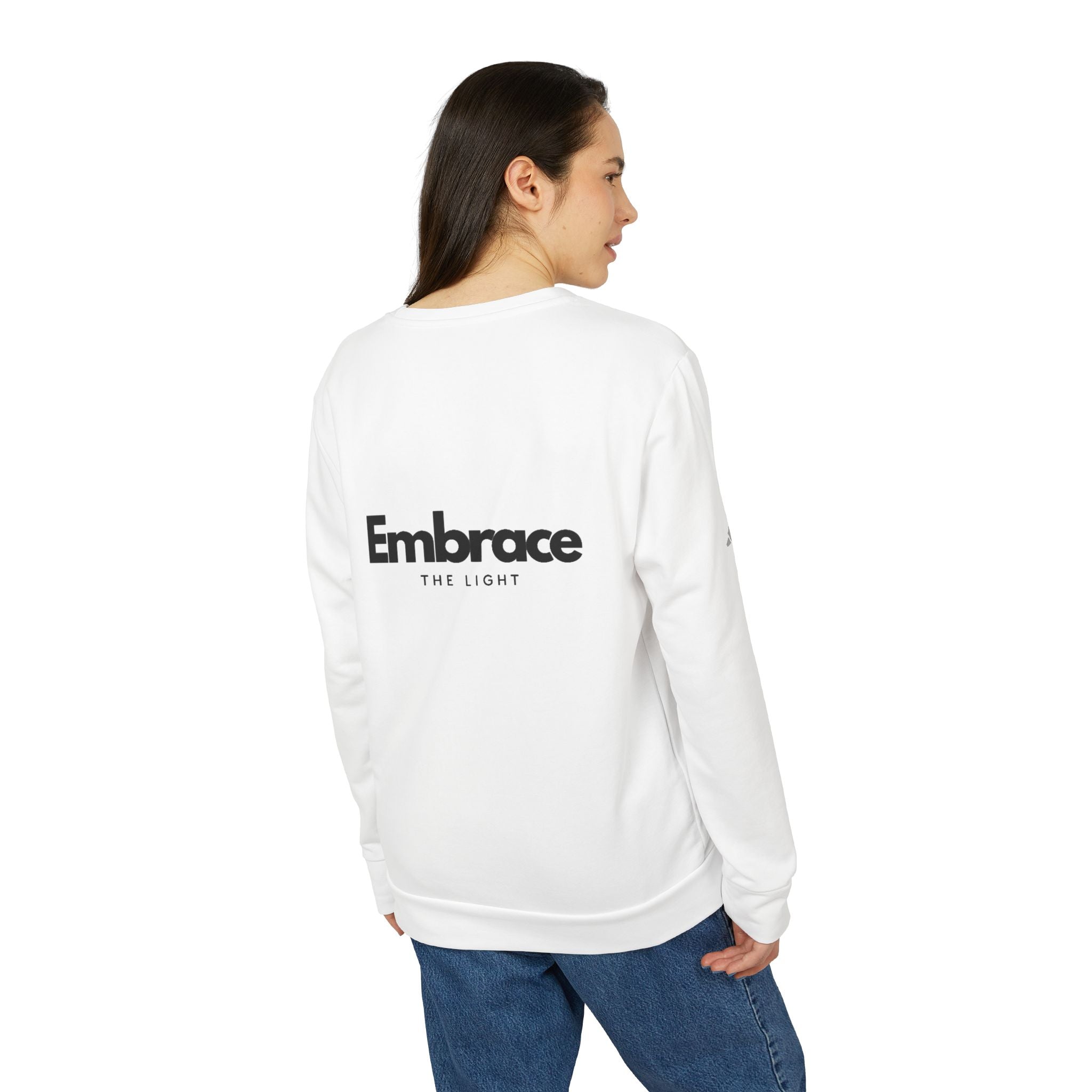 Adidas fleece sweatshirt in white with 'Embrace The Light' text on the back. Eco-friendly crewneck made from BCI cotton and recycled polyester for warmth and sustainability.